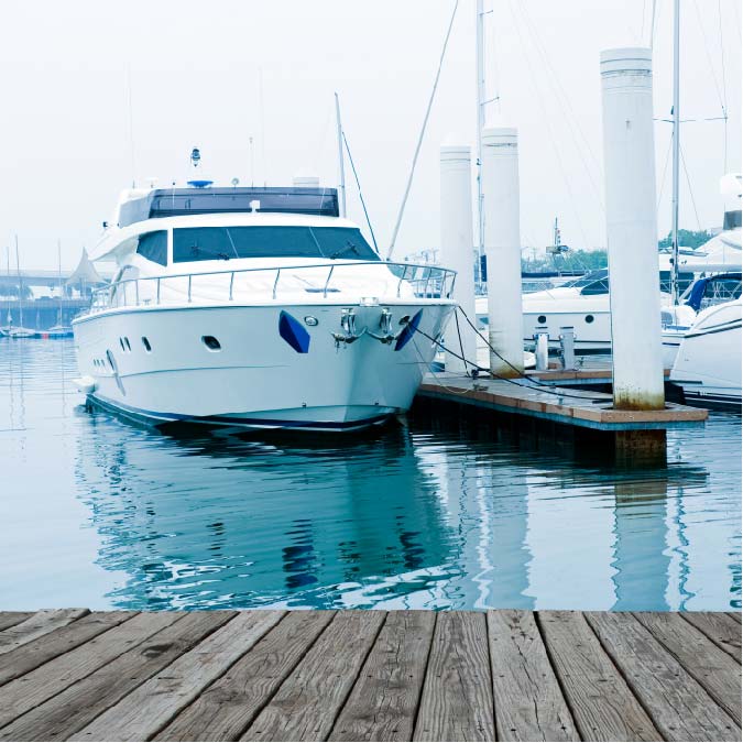 Image of a sleek motor yacht moored peacefully in a calm harbour, reflecting on the still sea.