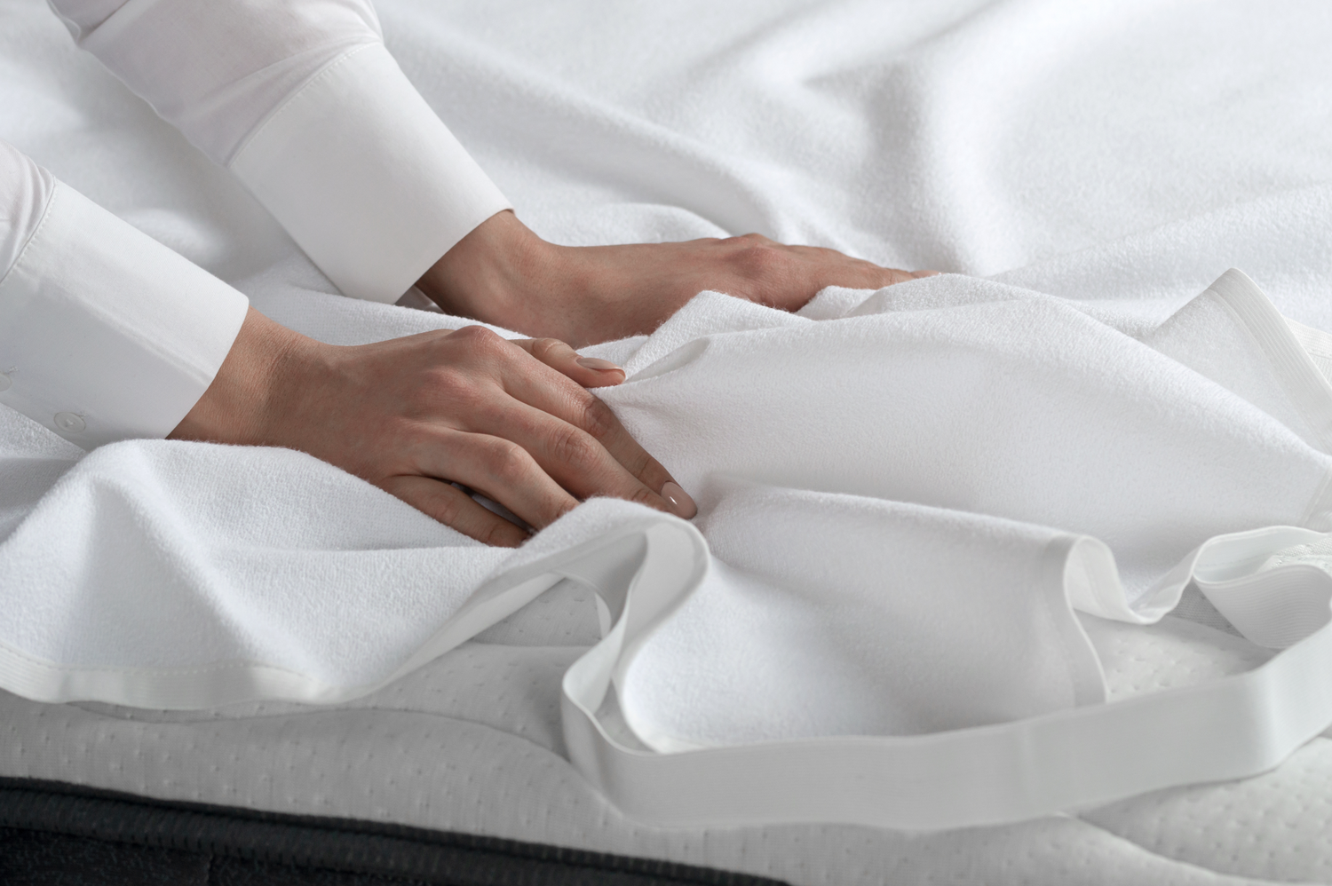 A girl changes the snow-white bed linen and places a mattress protector on the mattress to preserve the longevity of the mattress