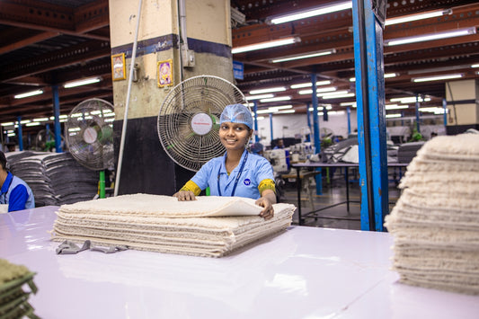 Factory worker smiles with cloth stacks.