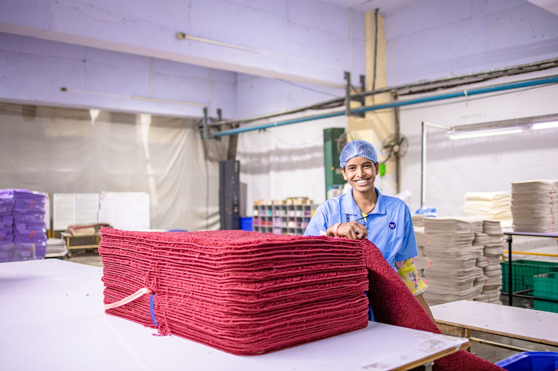 A worker smiles while handling folded textiles.