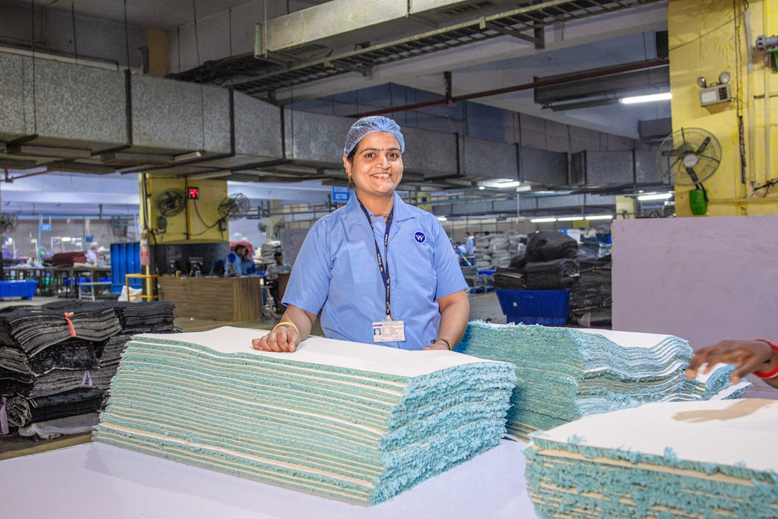 Factory worker standing near stacks of fabric.