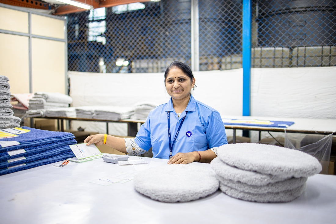 Woman works in a textile factory, smiling at camera.