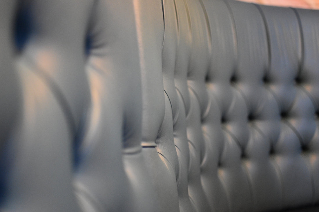 A leather couch back has detailed button tufting.
