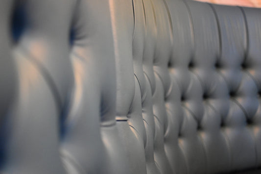 A leather couch back has detailed button tufting.
