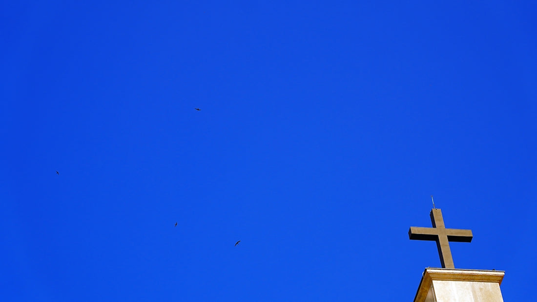 A cross on top of a building against blue sky