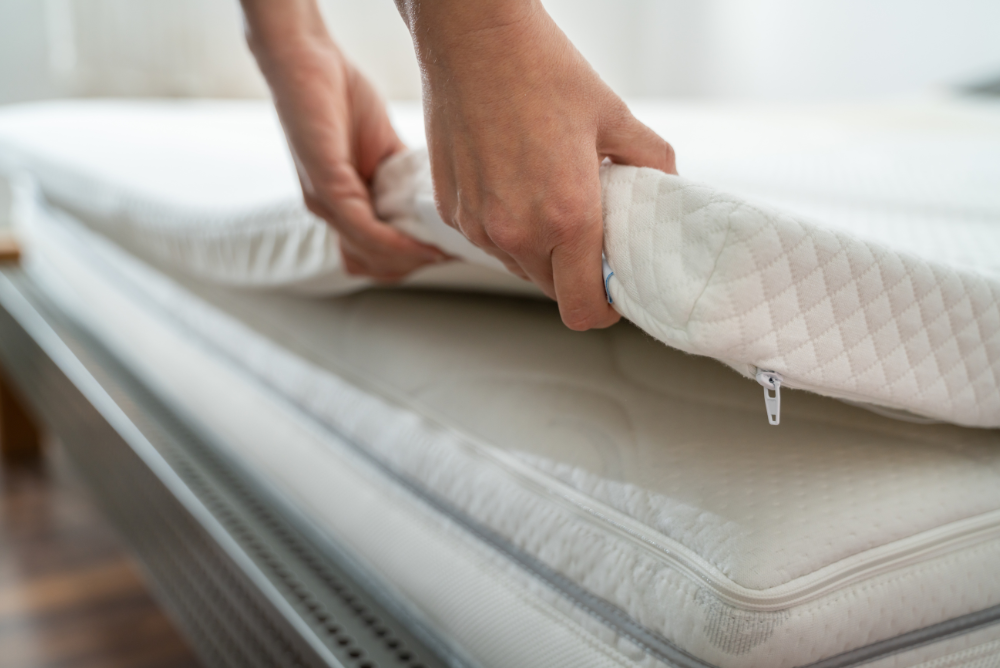 Hand laying a mattress topper onto a mattress, illustrating how easily the topper can be added for enhanced comfort and support.