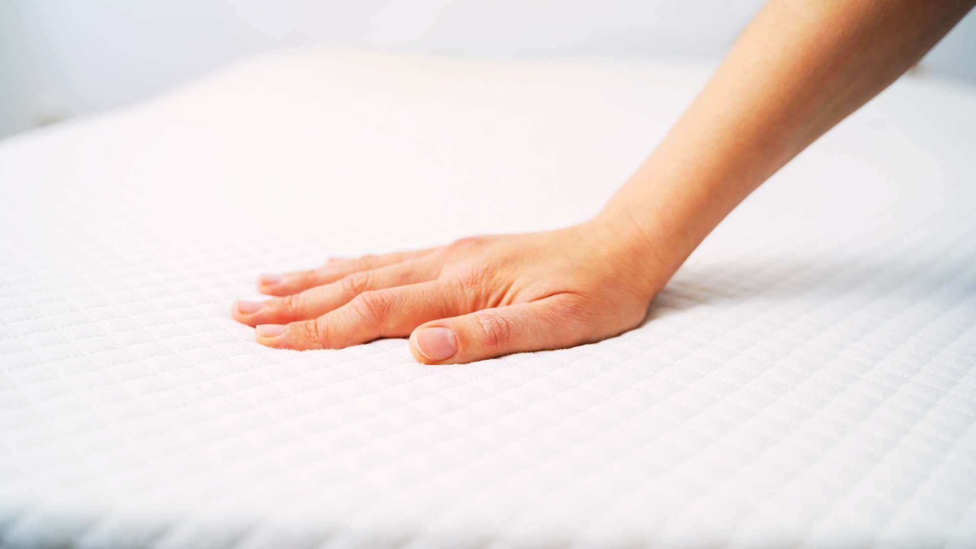 Hand pressing into a custom foam mattress, demonstrating its responsiveness.