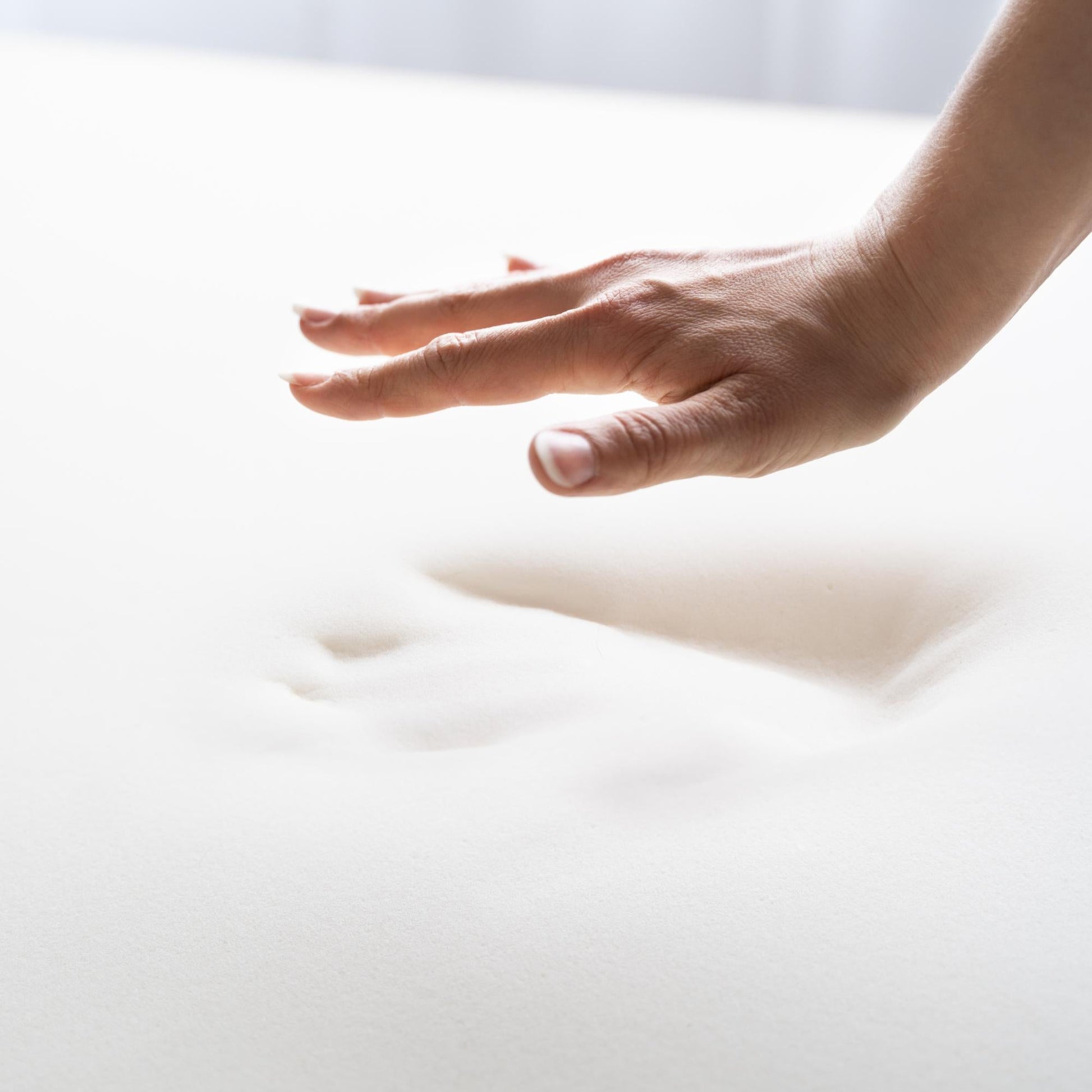 Hand pressing into memory foam, illustrating the supportive comfort it provides for caravan mattresses.
