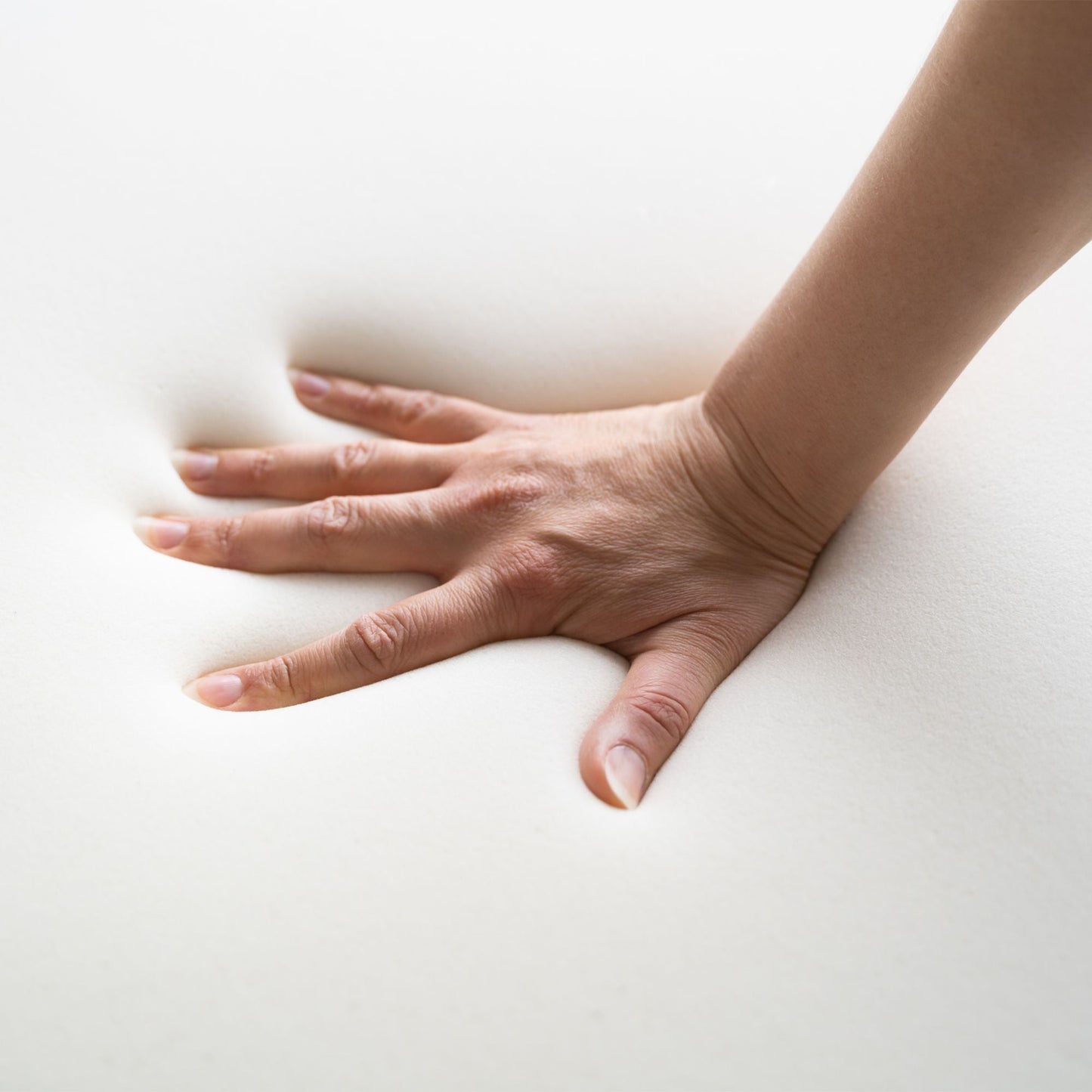 A Lady pushing her hand into a block of high density memory foam used inside the caravan mattress