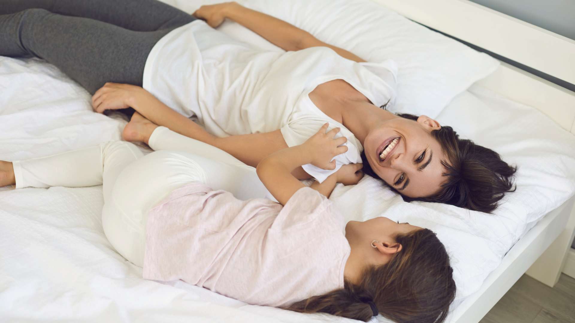 Mother and daughter laughing on a caravan mattress topper, enjoying a comfortable and custom-fit sleep.