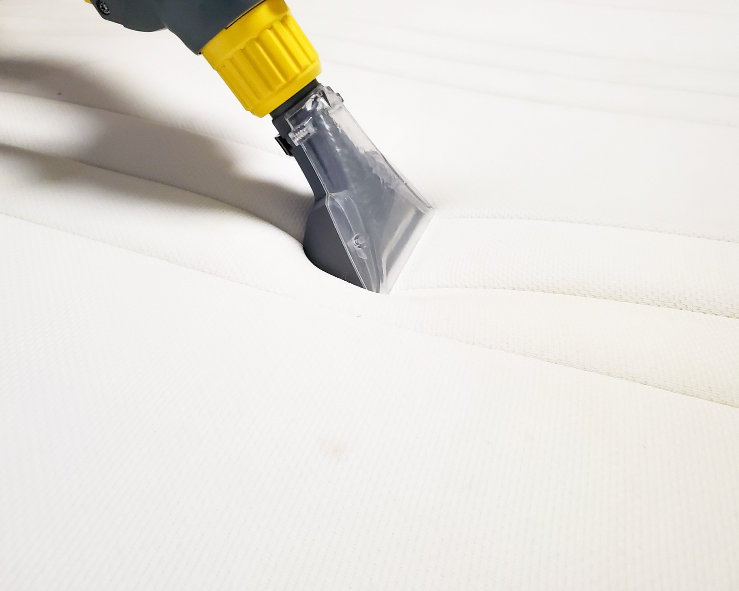 Dry cleaning tool actively cleaning the surface of a mattress cover, emphasizing the importance of regular maintenance for longevity and hygiene