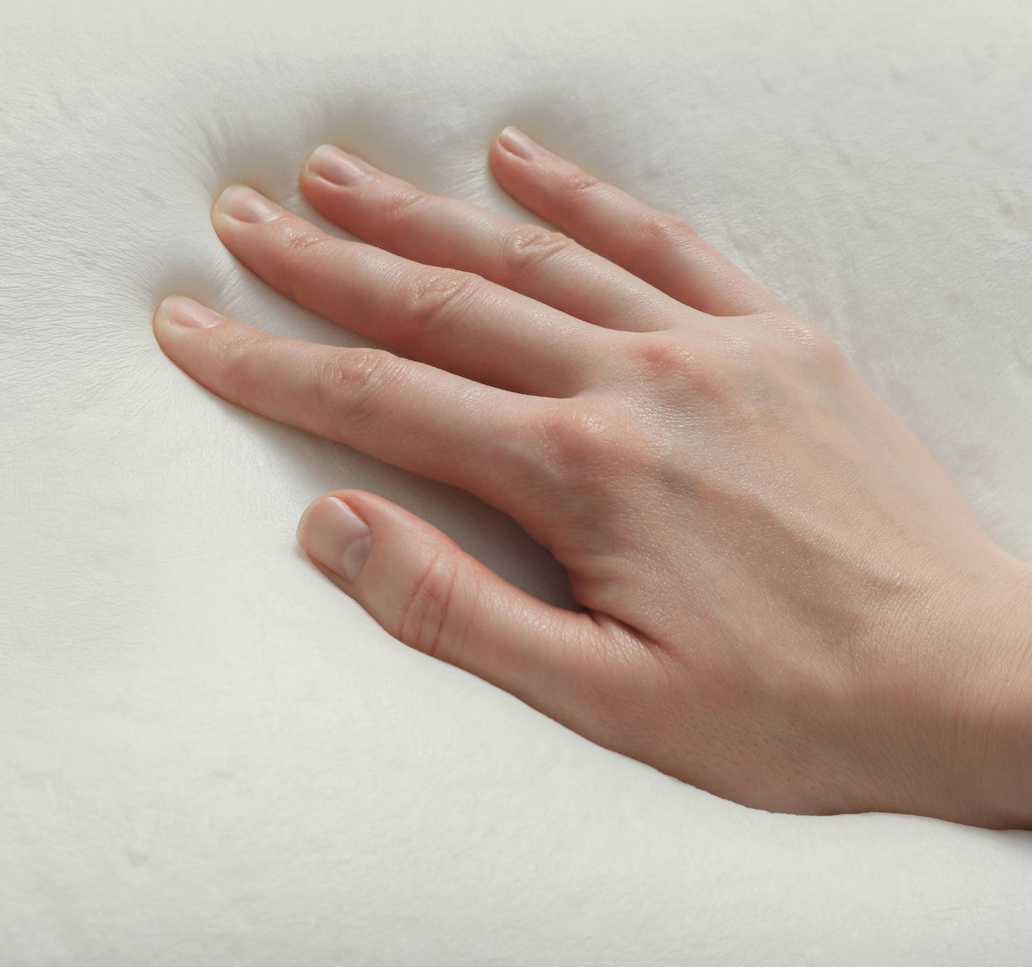 Hand pressing down on a layer of memory foam, demonstrating its responsiveness and contouring properties