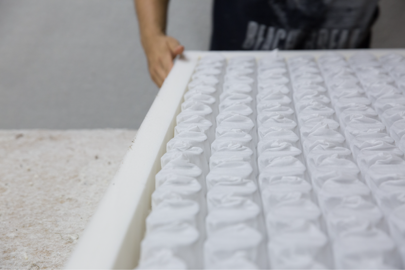 Pocket springs encased in foam displayed on a workbench, illustrating the internal components and craftsmanship of the mattress.