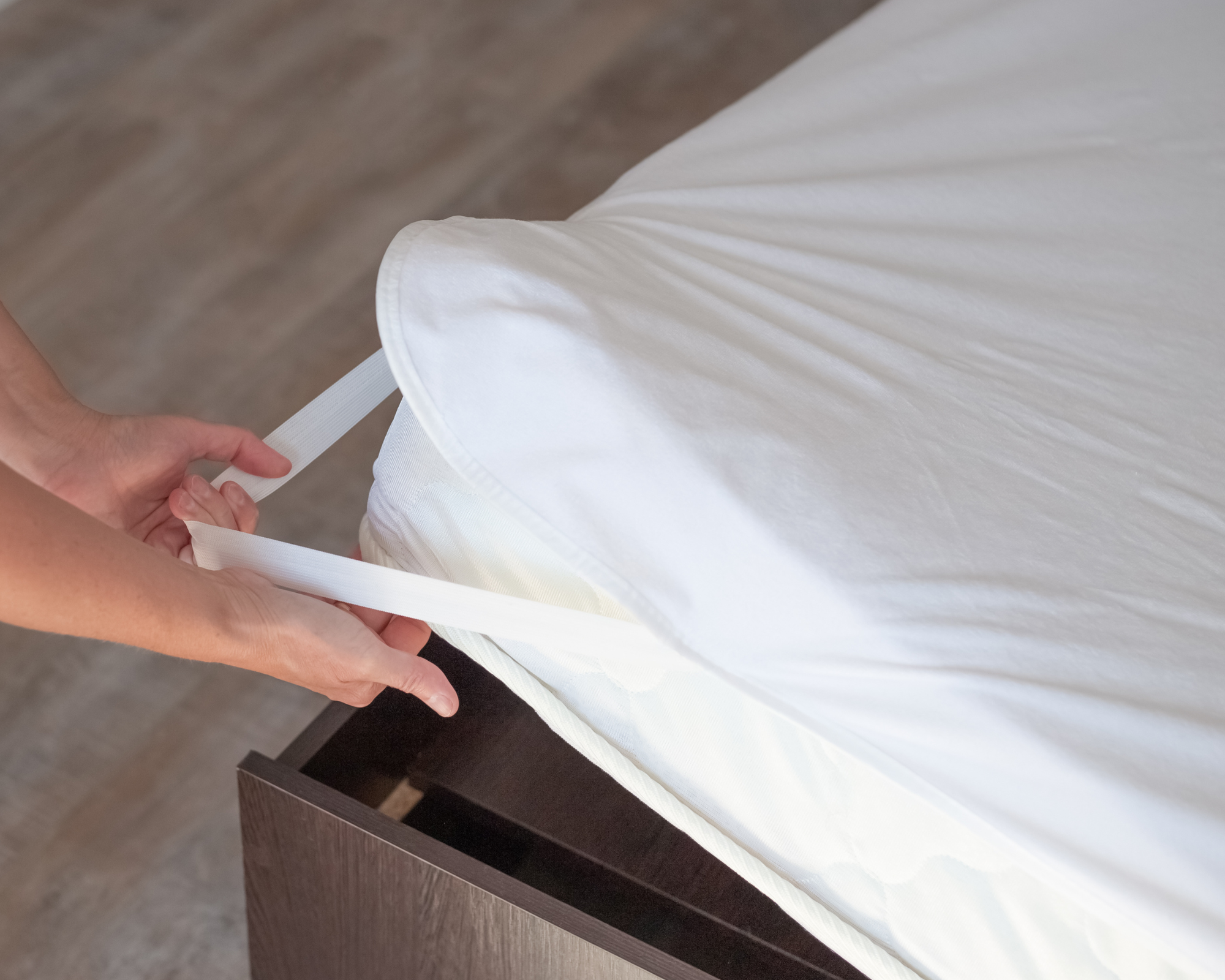 Waterproof mattress cover being securely fastened to a mattress using elastic straps, highlighting the protective and easy-to-install features.